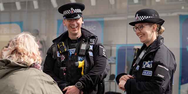 Two uniformed police officers talking to a person outdoors.