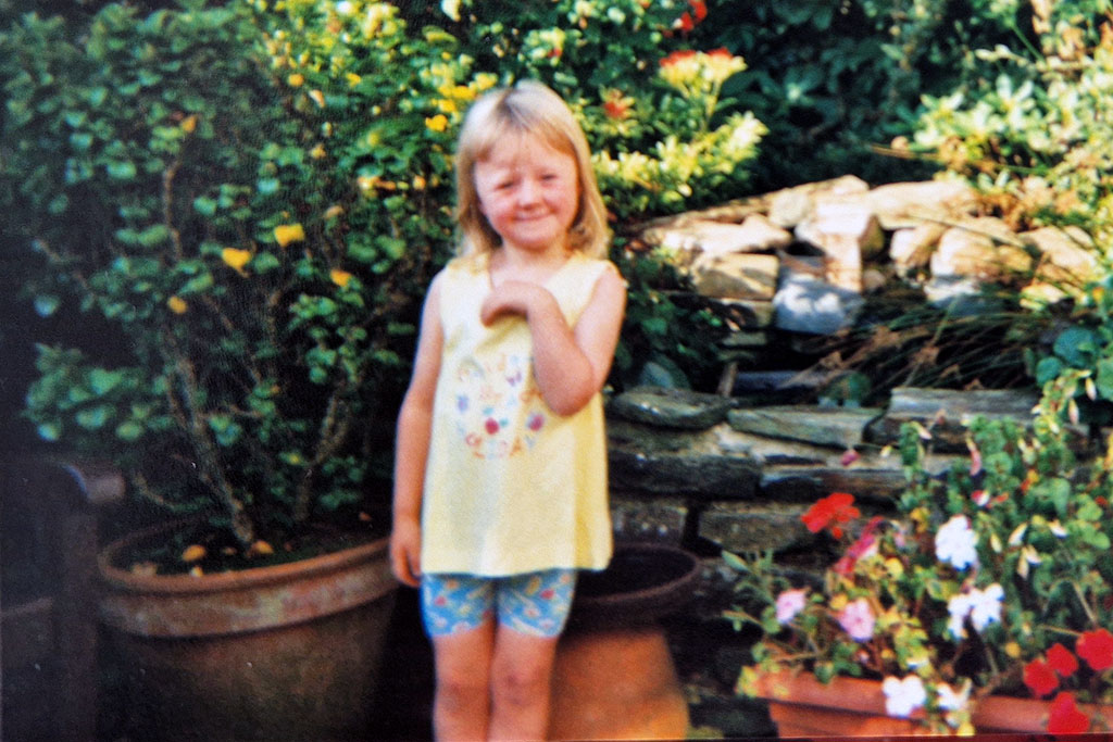 Annabel as a child standing in a garden of flowers