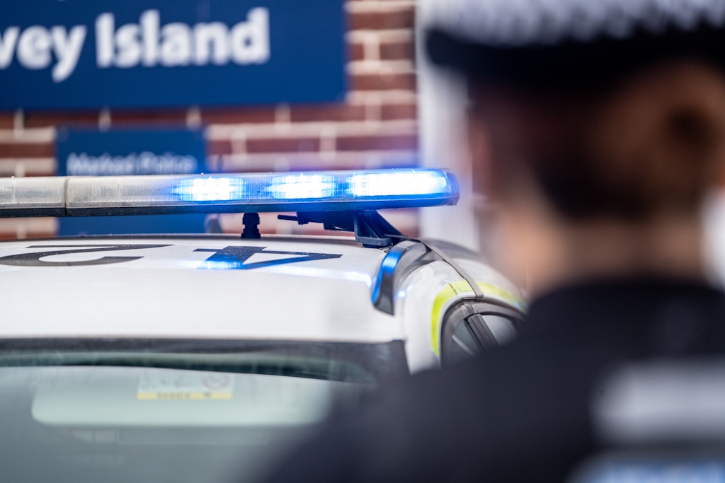 A uniformed Essex Police response officers and a police car with blue lights and the number 42 on its roof outside Canvey Island Police Station