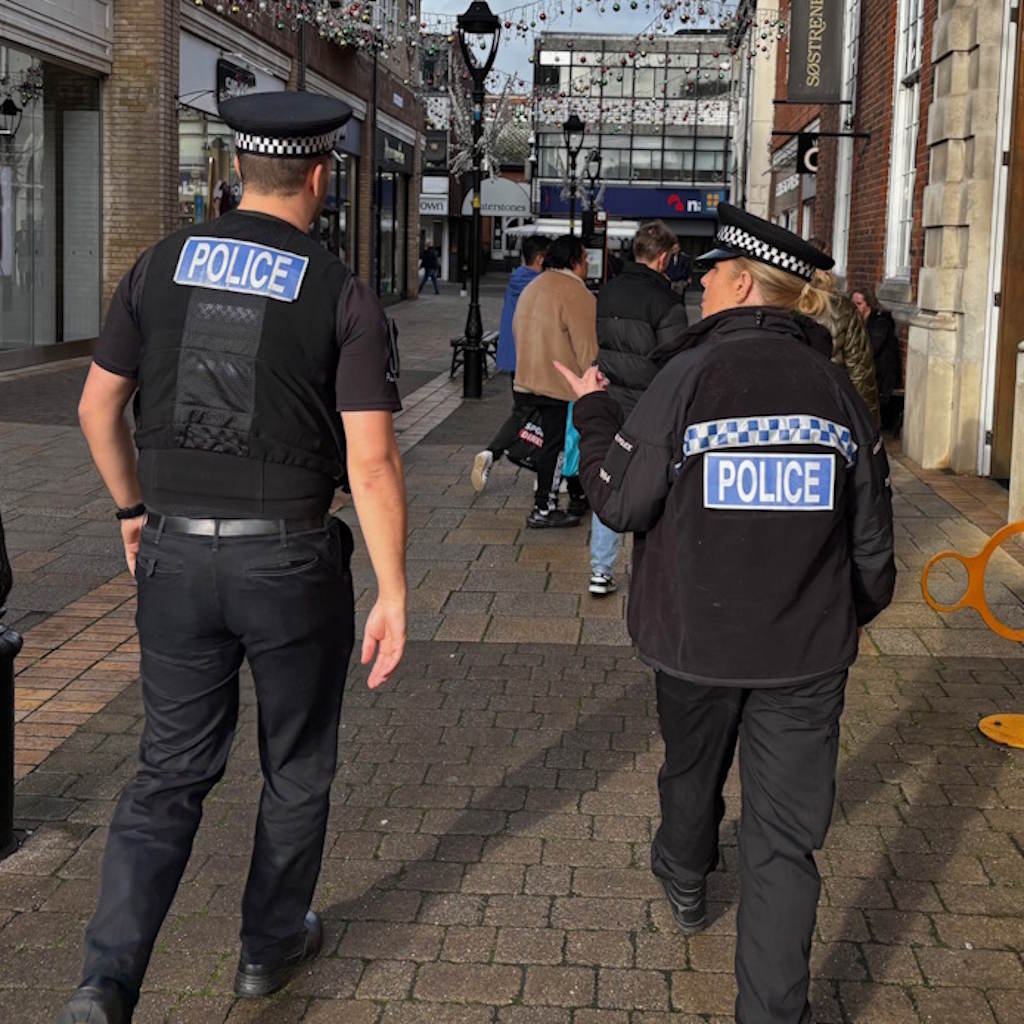 The back of two uniformed police officers patrolling a street