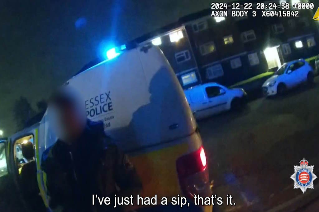 A suspect standing in front of a marked police vehicle