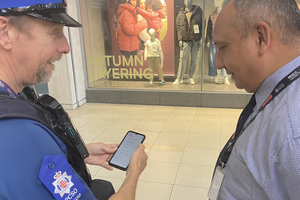 A uniformed Essex Police police community support officer and a business crime officer look at a mobile phone in a shopping centre
