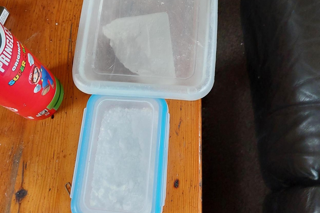 A block of cocaine and cocaine powder in plastic lunchboxes on a table