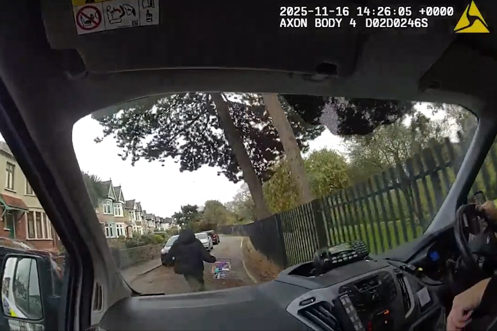 View through the windscreen of an Essex Police vehicle shows a man running up the road carrying a wire shopping basket