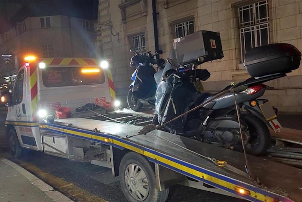 A seized motorbike is strapped on the back of a recovery lorry