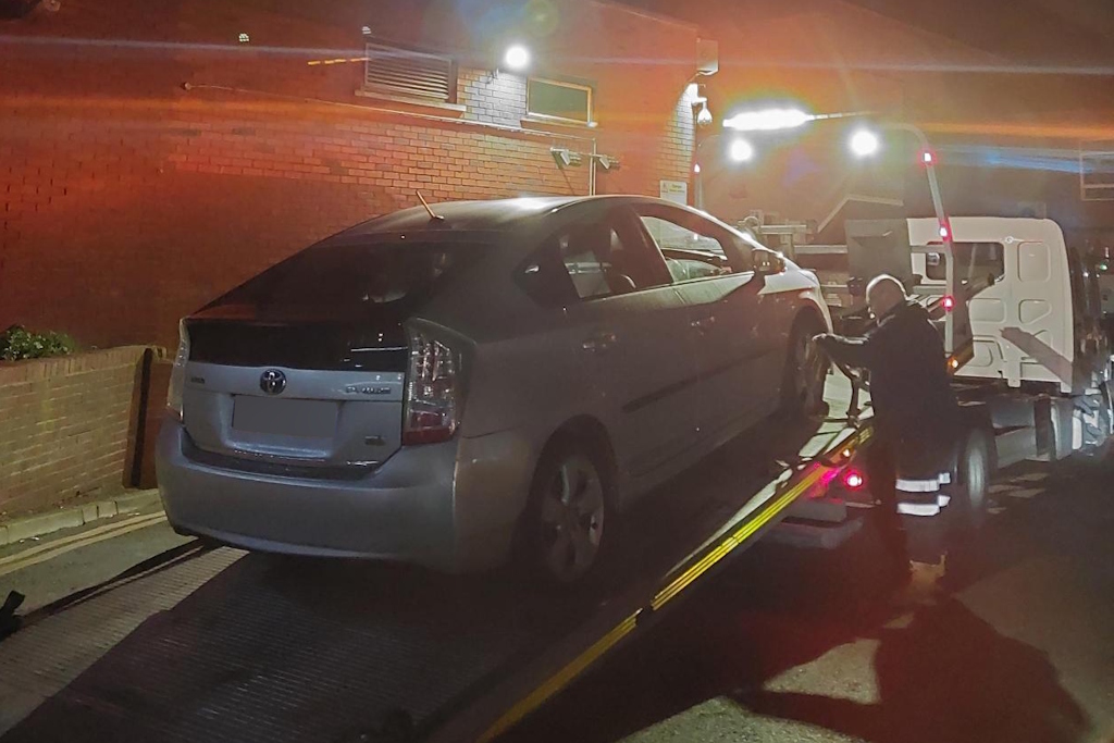 A seized car is strapped on the back of a recovery lorry