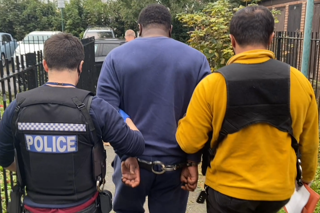A man handcuffed being led away by police officers