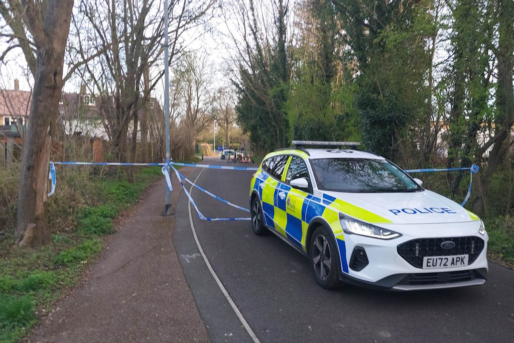 A marked police car before a police cordon on a cycle path