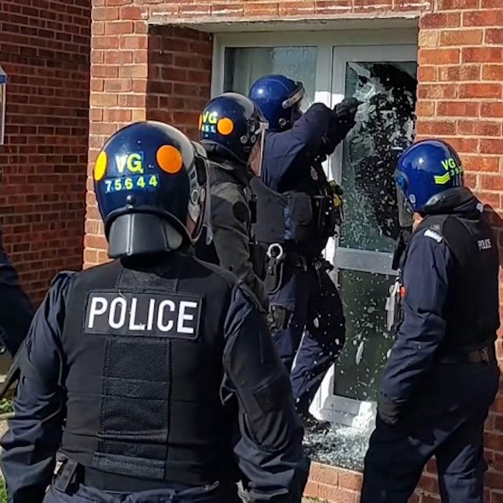 Uniformed officers smash a glass pane door