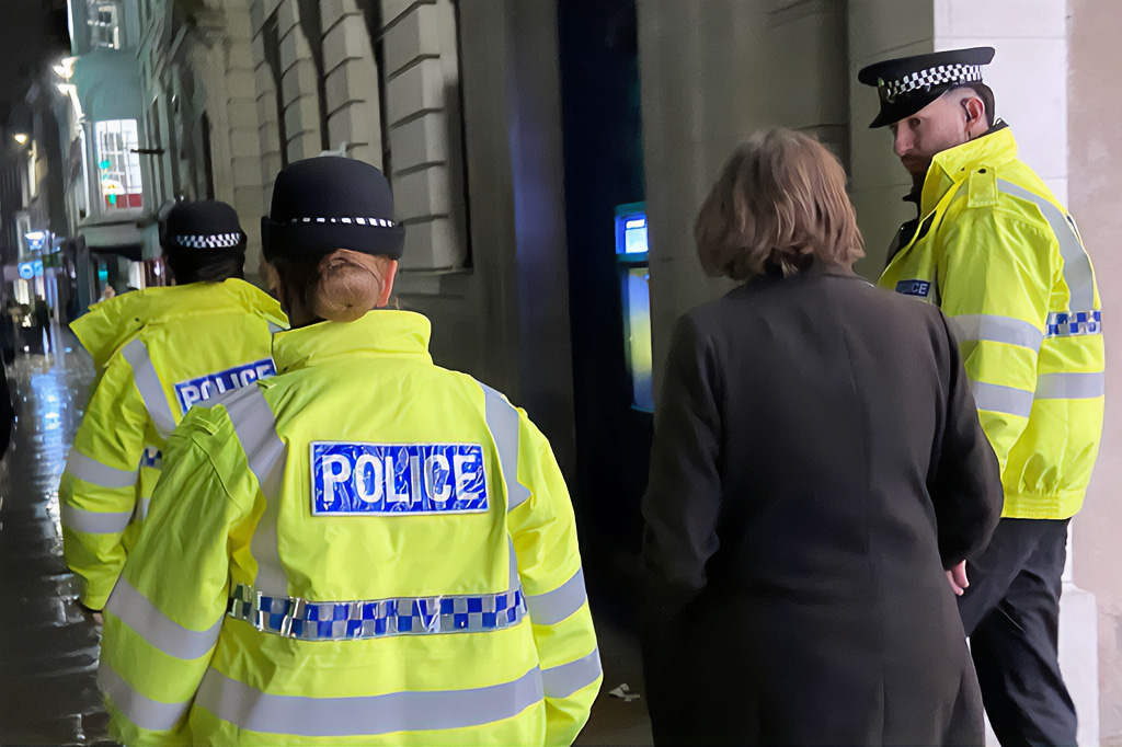 Essex Police officers walking with a visitor during a night-time patrol in Colchester.