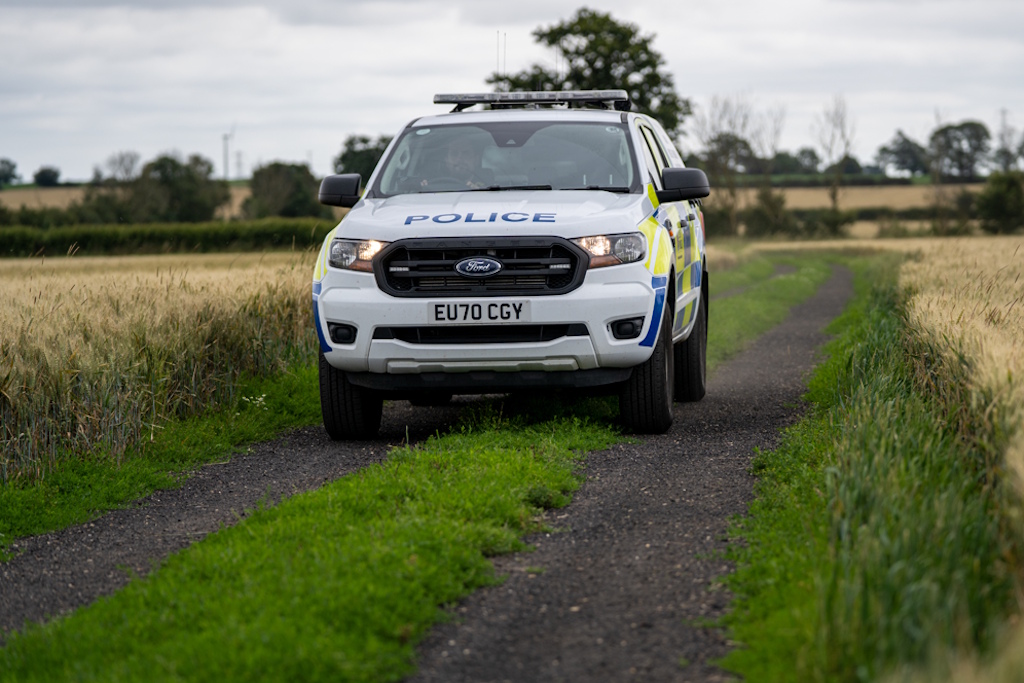 An Essex Police liveried Ford Ranger on a track through a cornfield