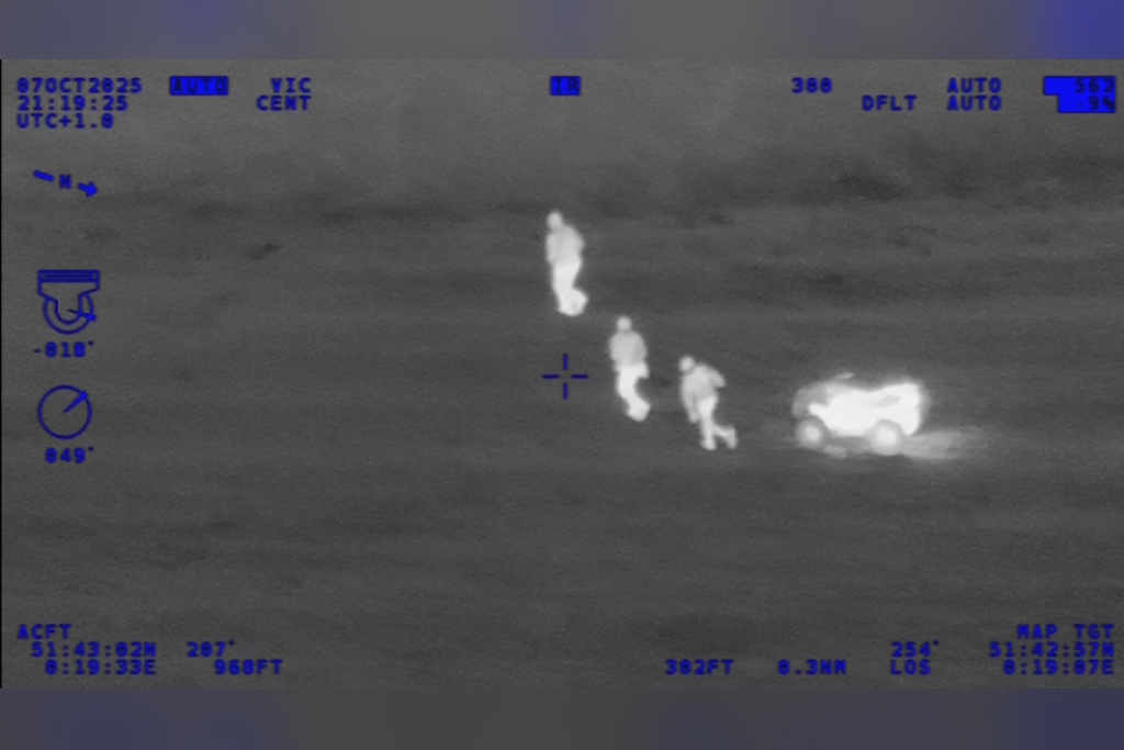 A screenshot of infra-red footage from a National Police Air Service helicopter showing three people running away from a quadbike in the middle of a field