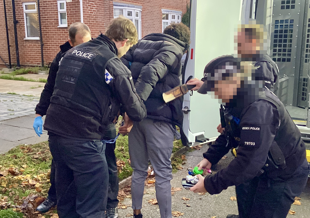 Uniformed officers surround a man held in handcuffs