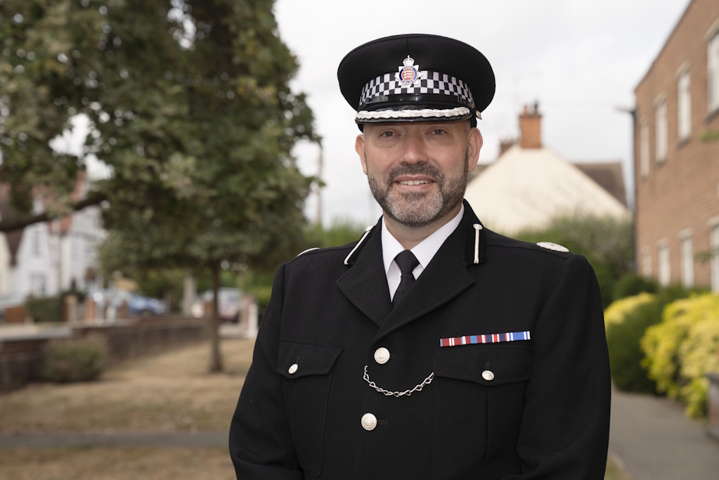 An Essex Police assistant chief constable in ceremonial uniform, with trees and houses in the background