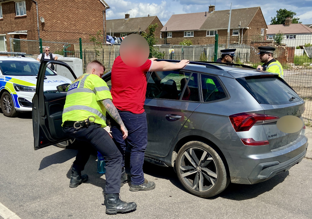 A man is searched against a car.