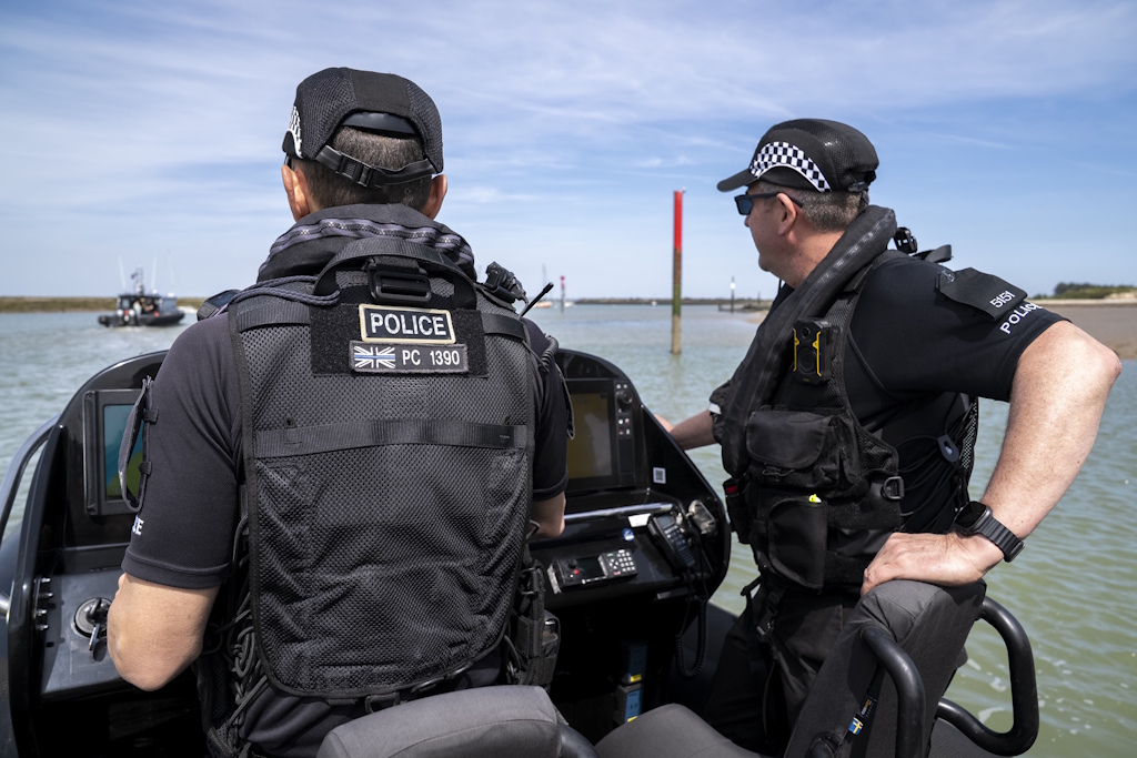 Two uniformed Essex Police Marine Unit officers aboard a rigid-hulled inflatable boat, or rib, heading out to sea on patrol