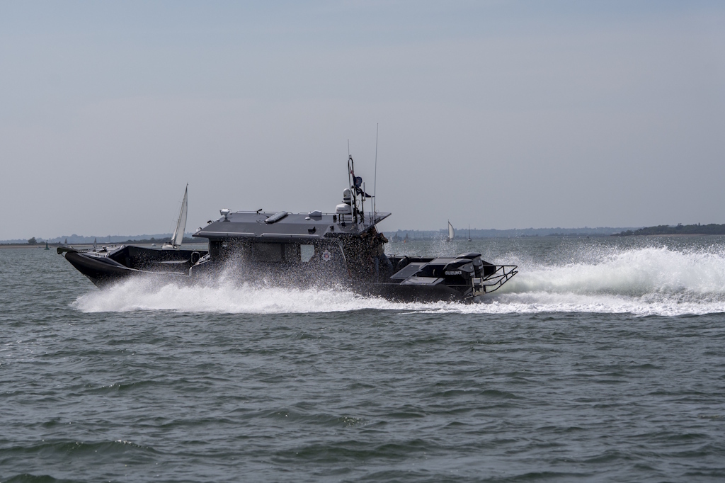 Side-view of a police launch patrolling at speed at sea. There is a big wake alongside and behind the boat