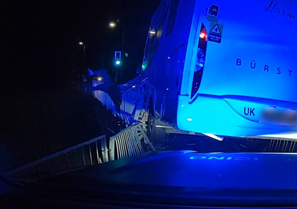 A man flips over railings by a crashed motorhome.