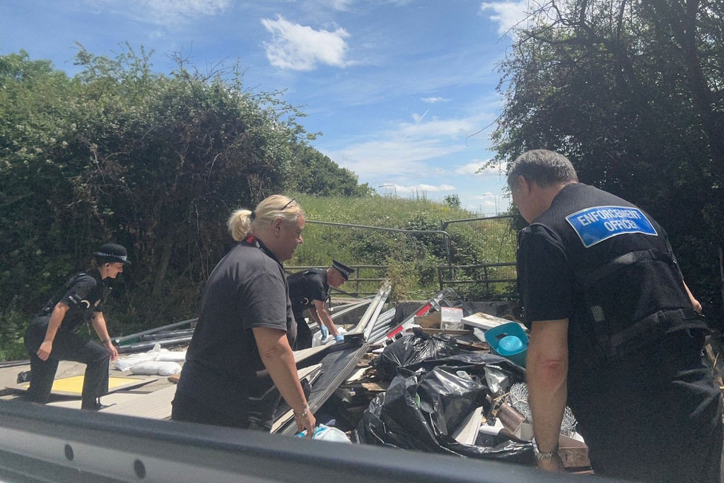 Uniformed Essex Police neighbourhood policing officers and two Brentwood Borough Council enforcement officers examine a pile of fly-tipped waste in the gateway to a field