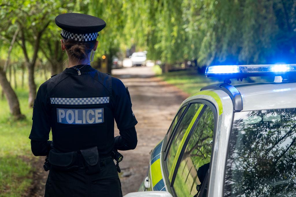 uniformed police officer next to car