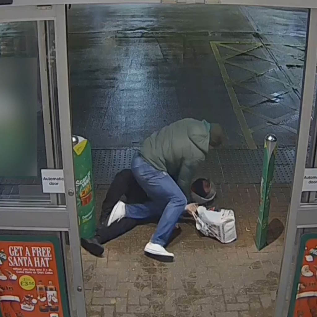 CCTV image shows man in green jacket holding a masked man on the floor