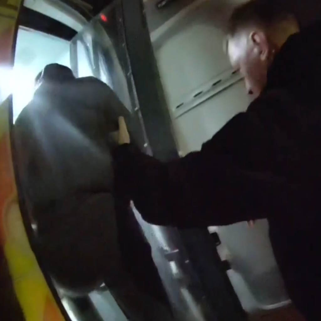 A man in a grey tracksuit is helped into a police van