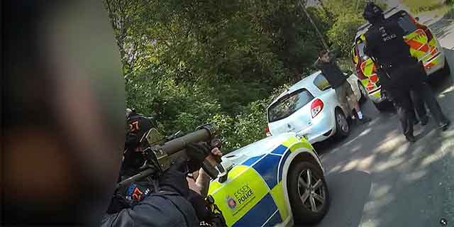 Essex Police officers beside a white car on a rural road, with a firearm officer in the foreground.