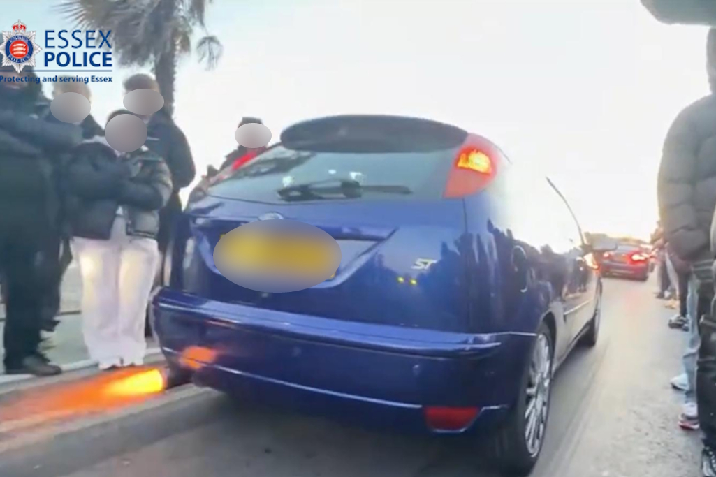 Blue car on road beside group on pavement