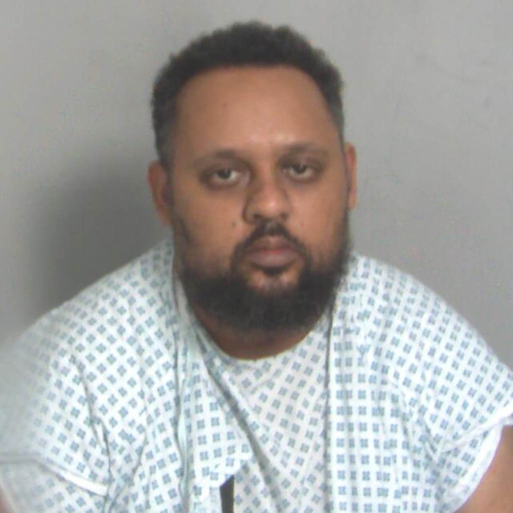 Custody image shows bearded man wearing hospital gown