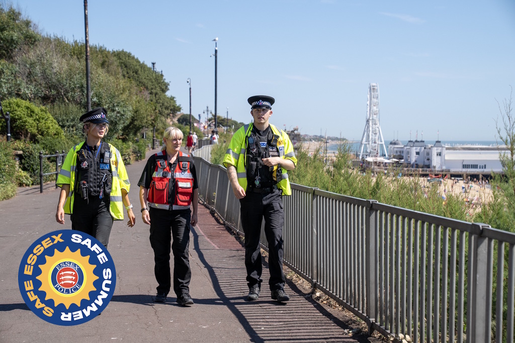 Two uniformed Essex Police neighbourhood policing officers patrolling along a seafront with a uniformed Tendring District Council community safety officer