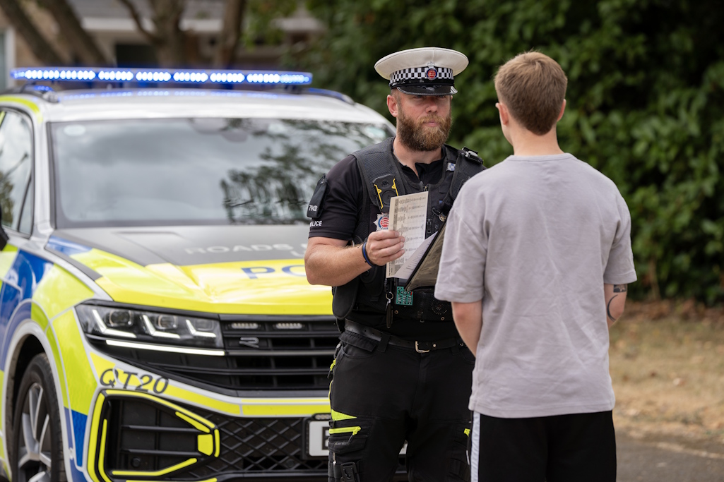 Police officer spoeaking to driver in frPolice officer speaking to driver in front of police caront of police car