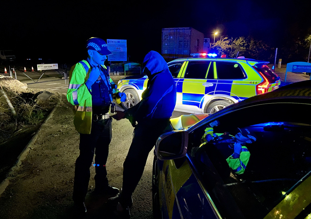Am arrested man leans against a police car.